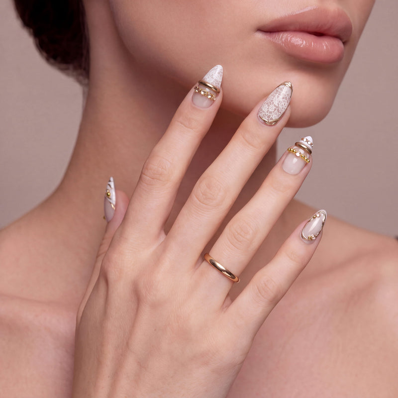 Wild Romance Fantasy handmade press-on nails on a hand model with white lace texture, gold beads, and nude bases