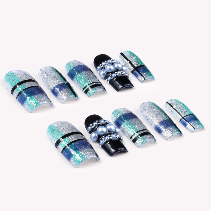 Diagonal flat lay of Winter Gridlight press-on nails with silver glitter, aqua blue, black, and pearl accents