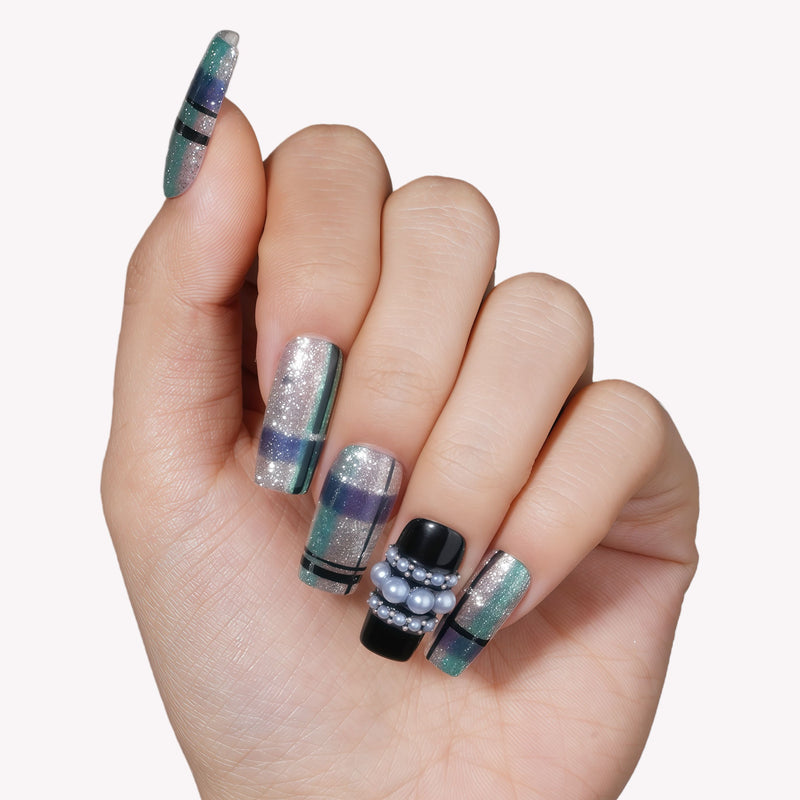 Hand model wearing Winter Gridlight press-on nails with silver glitter, aqua blue, black, and pearl accents
