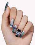 Hand model wearing Winter Gridlight press-on nails with silver glitter, aqua blue, black, and pearl accents