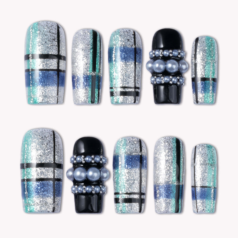 Flat lay of Winter Gridlight press-on nails with silver glitter, aqua blue, black, and pearl accents arranged in two rows